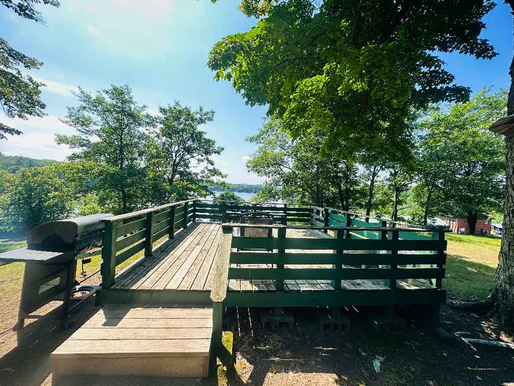 Flying Eagle’s wooden deck and lake, shaded by leafy trees